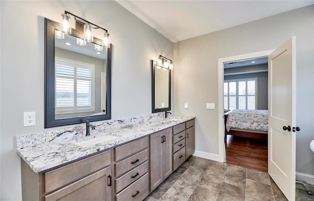 bathroom featuring double vanity, ensuite bath, baseboards, and a sink