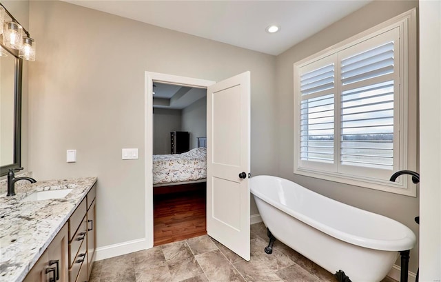 ensuite bathroom featuring a freestanding tub, baseboards, ensuite bath, and vanity