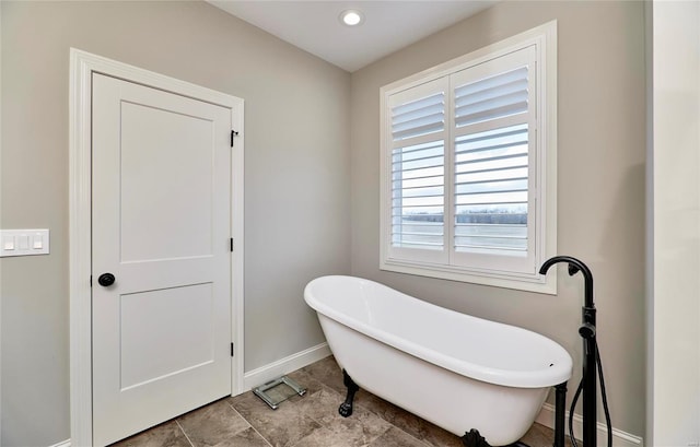 bathroom featuring baseboards and a freestanding bath