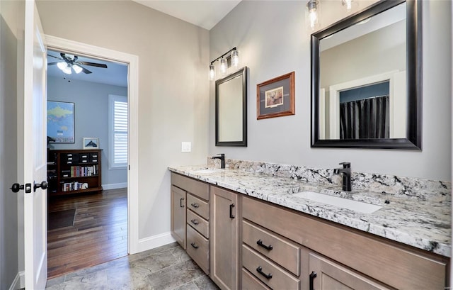 bathroom featuring ceiling fan, double vanity, baseboards, and a sink