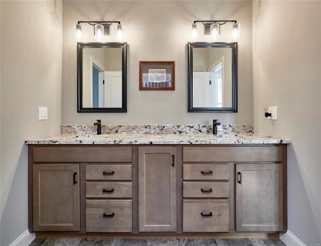 bathroom with double vanity, baseboards, and a sink