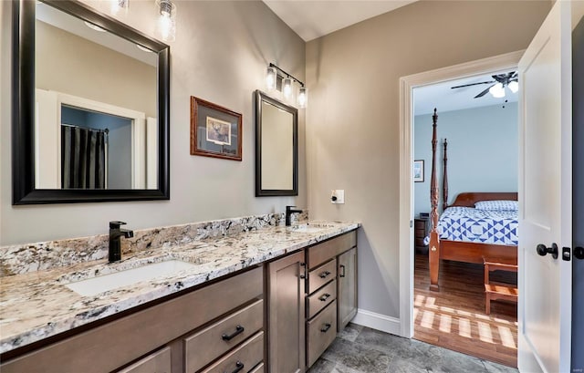 bathroom featuring a sink, baseboards, ceiling fan, and double vanity