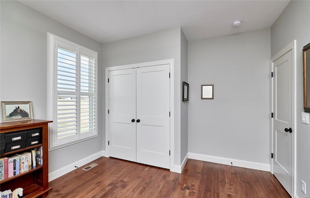 interior space featuring dark wood finished floors, baseboards, and a closet