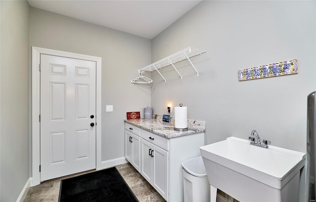 clothes washing area featuring a sink and baseboards