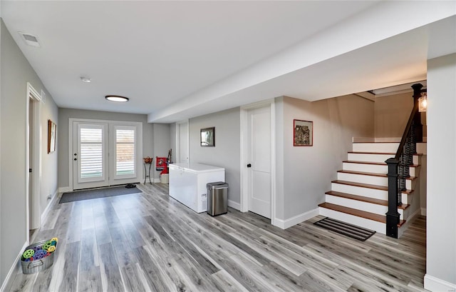 interior space featuring visible vents, light wood-style flooring, stairs, and baseboards