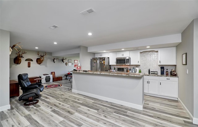 kitchen with stainless steel appliances, light wood finished floors, visible vents, and white cabinetry