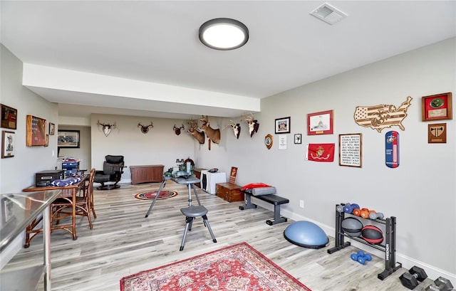 exercise area featuring visible vents, baseboards, and light wood-style floors