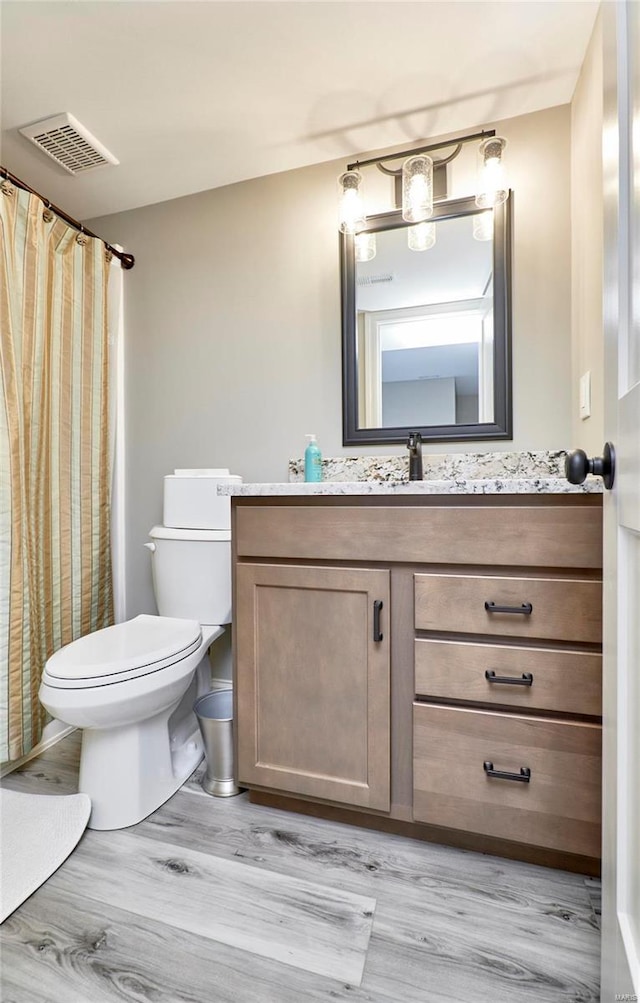 full bathroom with visible vents, toilet, vanity, and wood finished floors