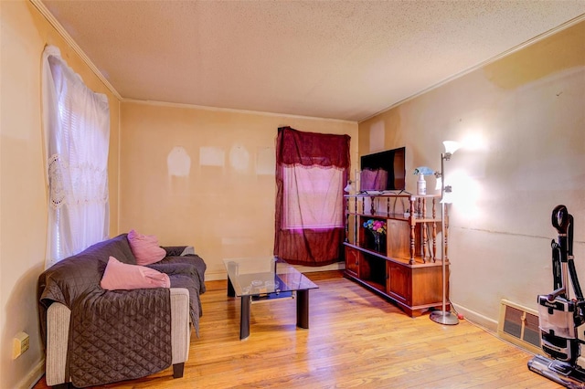 sitting room with crown molding, light hardwood / wood-style flooring, and a textured ceiling