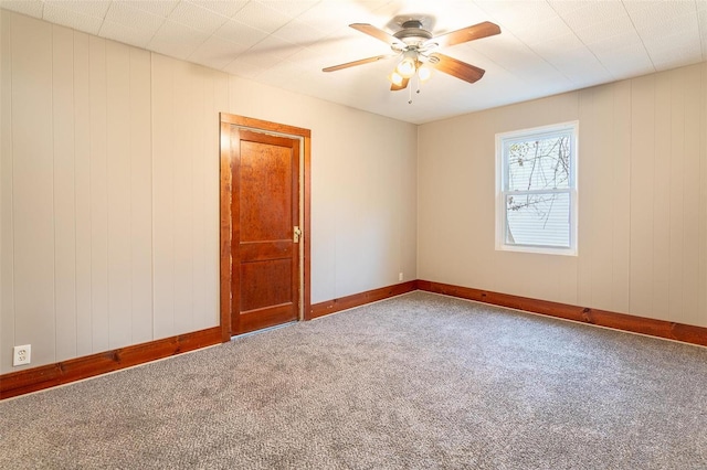 unfurnished room featuring carpet flooring, ceiling fan, and wooden walls