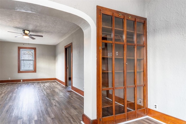 spare room with ceiling fan, a textured ceiling, and dark wood-type flooring