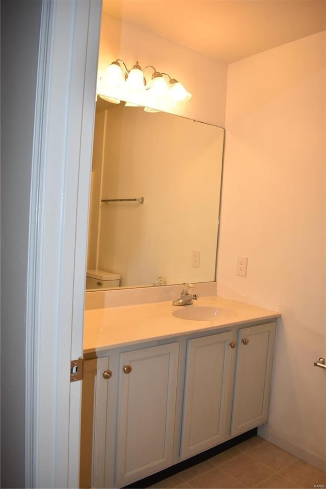 bathroom with toilet, vanity, and tile patterned floors