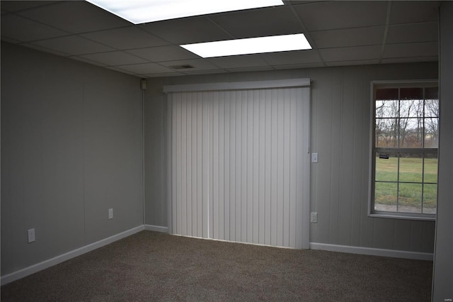 carpeted spare room with a drop ceiling and a wealth of natural light