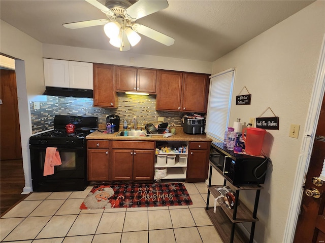 kitchen featuring light countertops, gas stove, light tile patterned flooring, a sink, and under cabinet range hood