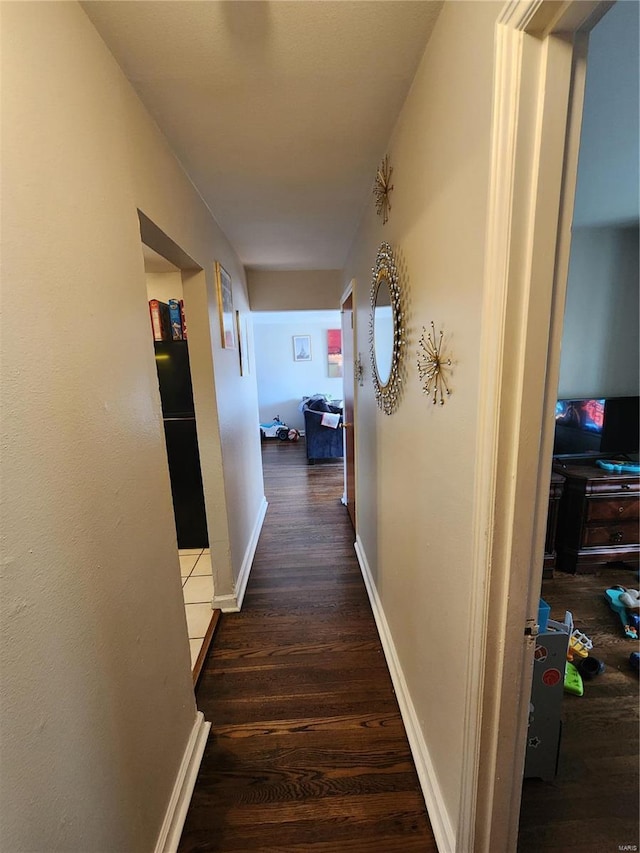 hallway with dark wood-type flooring and baseboards