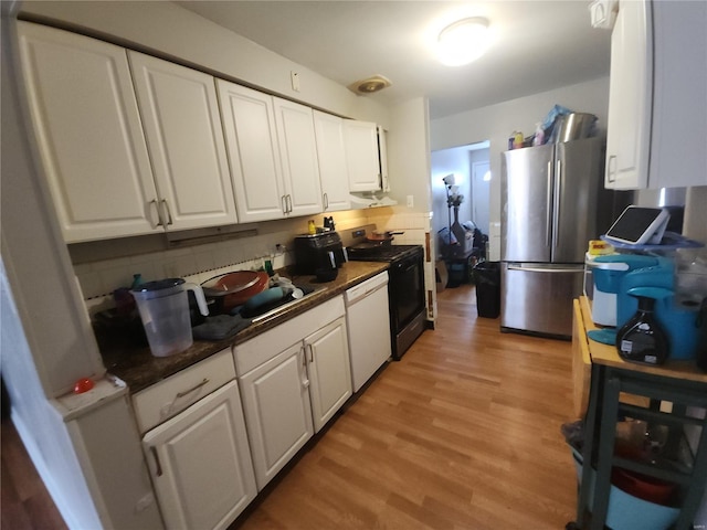 kitchen with freestanding refrigerator, stove, dark countertops, and white cabinetry