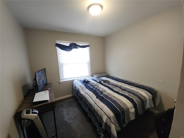 bedroom featuring baseboards and dark carpet