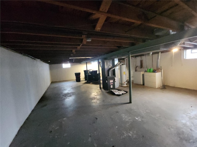 basement with washing machine and dryer, gas water heater, and heating unit