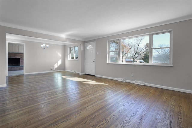 interior space featuring a chandelier, dark wood-type flooring, and a brick fireplace