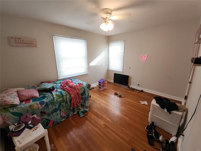 bedroom featuring a ceiling fan, baseboards, and wood finished floors