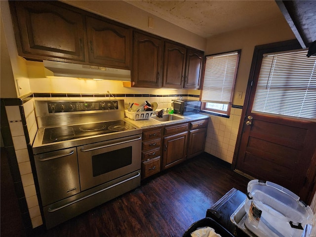 kitchen with sink, dark brown cabinets, tile walls, double oven range, and dark hardwood / wood-style flooring