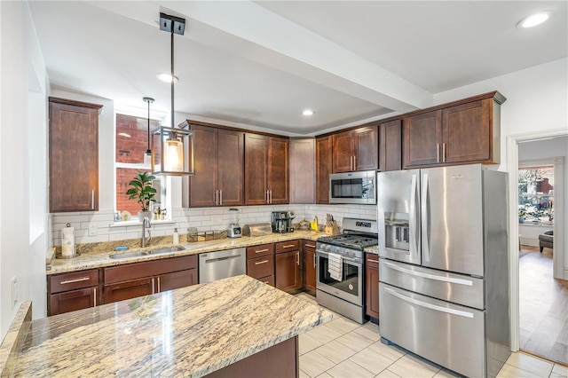 kitchen featuring sink, stainless steel appliances, tasteful backsplash, light stone counters, and pendant lighting