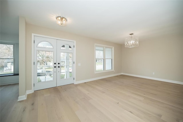 doorway to outside with french doors, light wood-type flooring, and a notable chandelier