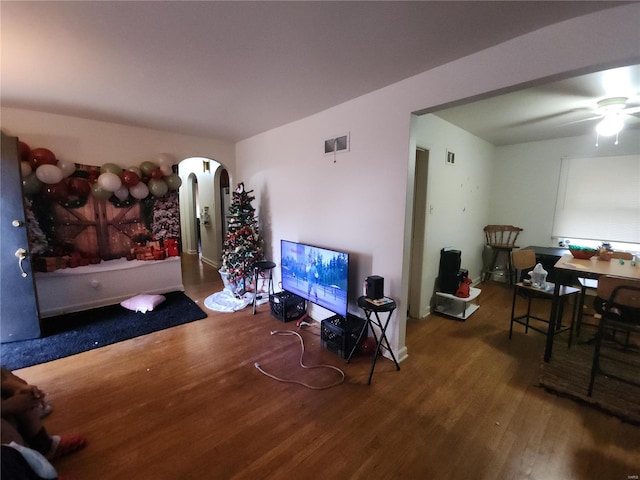 living room with a ceiling fan, visible vents, arched walkways, and wood finished floors