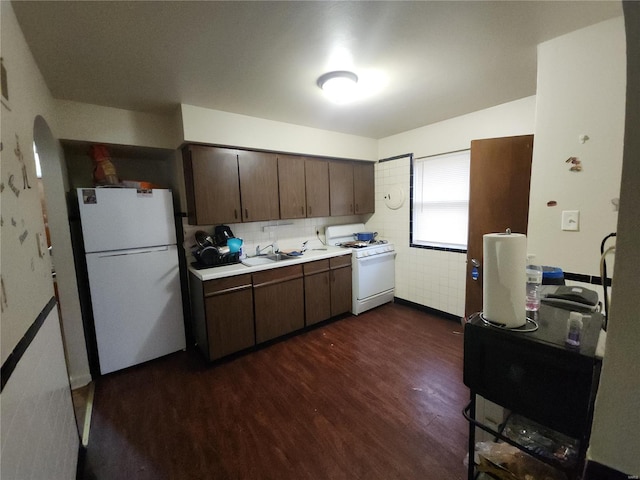 kitchen featuring dark wood finished floors, light countertops, a sink, dark brown cabinets, and white appliances