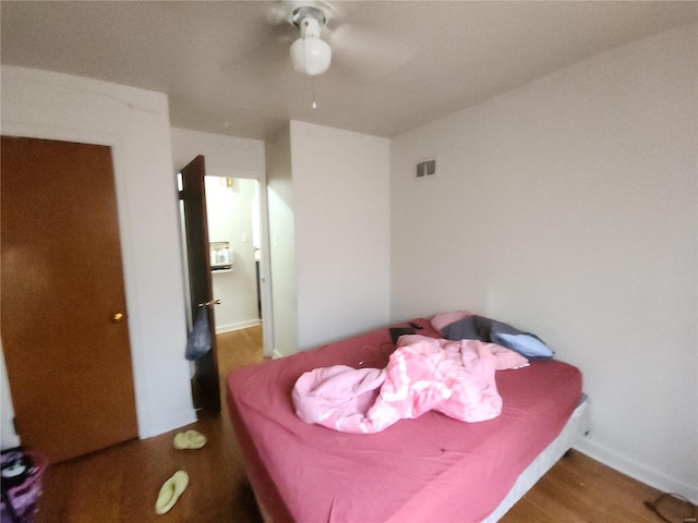 bedroom with a ceiling fan, visible vents, and wood finished floors