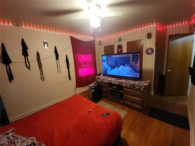 cinema room with ceiling fan and wood finished floors