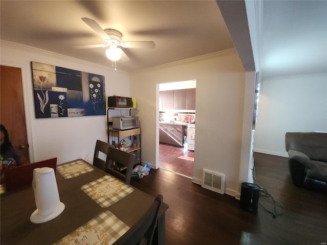 dining area featuring dark wood-type flooring, a ceiling fan, baseboards, visible vents, and crown molding