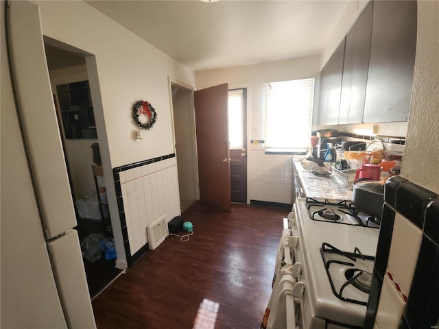 kitchen featuring white appliances, wainscoting, dark wood-style floors, light countertops, and tile walls