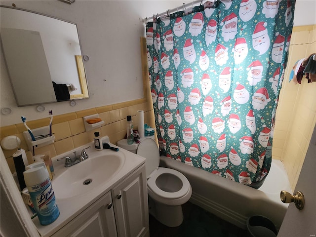 bathroom with a wainscoted wall, tile walls, toilet, shower / tub combo, and vanity