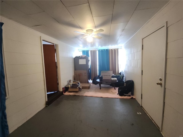 interior space featuring ceiling fan and concrete block wall