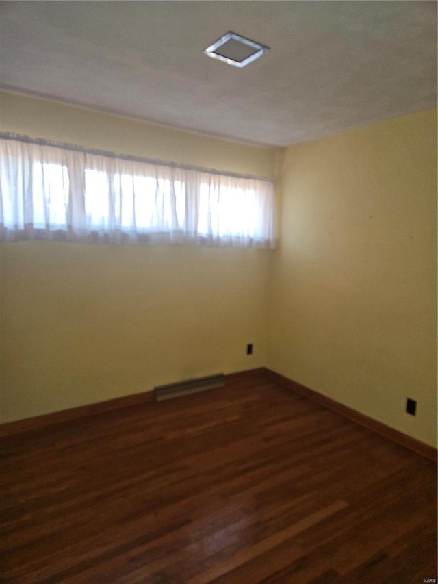 empty room featuring dark hardwood / wood-style flooring and a baseboard radiator