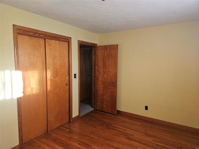 unfurnished bedroom featuring dark hardwood / wood-style flooring and a closet