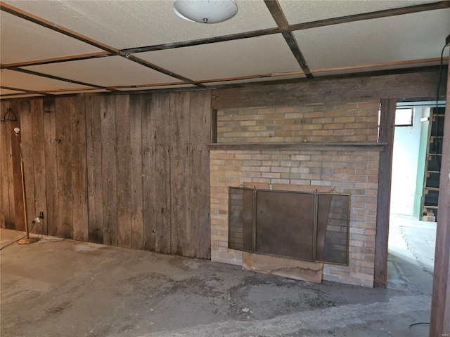 basement with a brick fireplace and wood walls