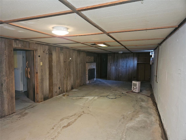 basement with wood walls and a brick fireplace