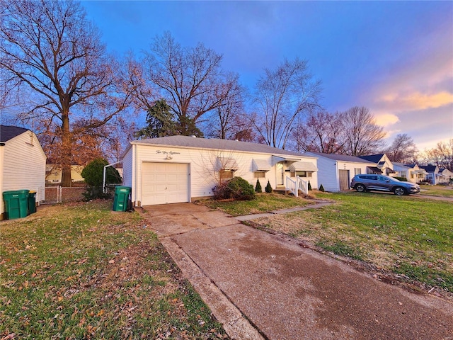 ranch-style house with concrete driveway, a yard, and an attached garage