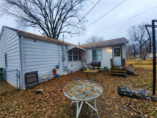 rear view of property featuring entry steps and fence