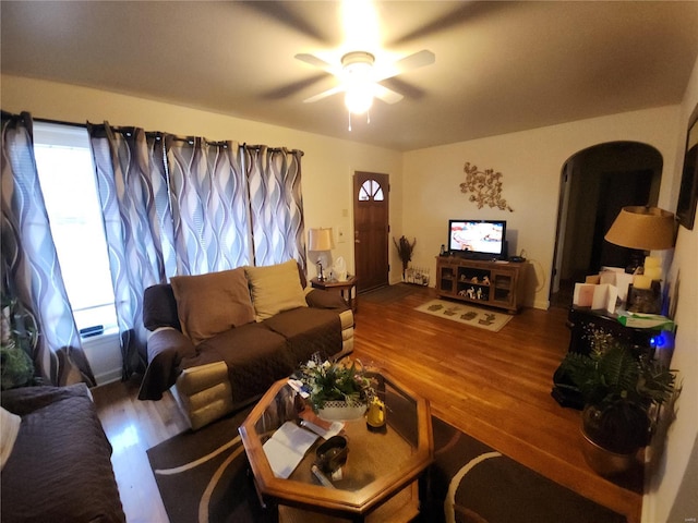 living area with a ceiling fan, arched walkways, and wood finished floors