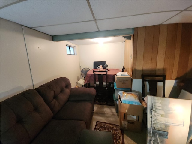 living area featuring a drop ceiling and wood walls