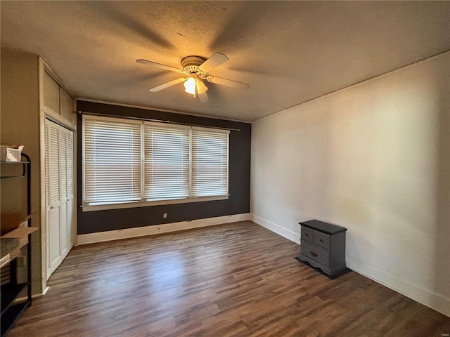 interior space with a textured ceiling, ceiling fan, and dark hardwood / wood-style floors