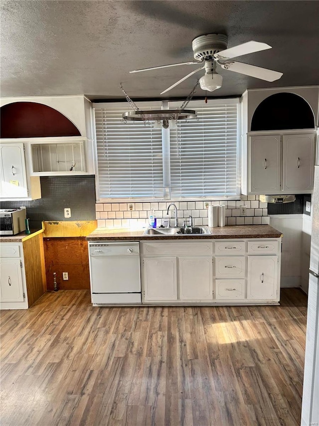 kitchen featuring white dishwasher, backsplash, light wood-type flooring, and sink