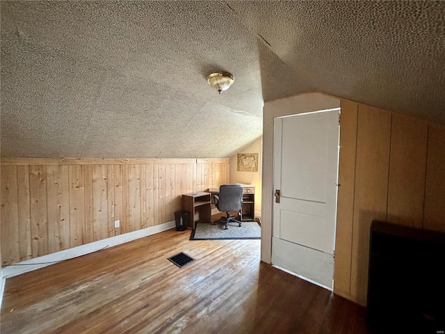 additional living space featuring hardwood / wood-style floors, a textured ceiling, and lofted ceiling