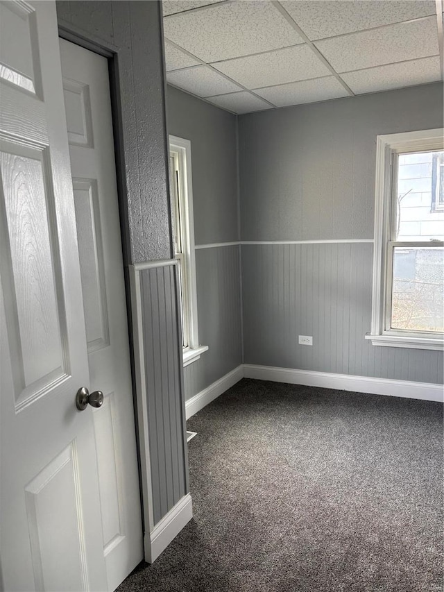 unfurnished room featuring carpet and a paneled ceiling