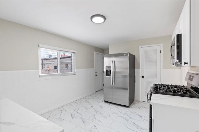 kitchen featuring appliances with stainless steel finishes, white cabinetry, and light stone counters