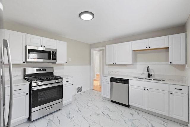 kitchen featuring light stone countertops, white cabinetry, sink, and stainless steel appliances