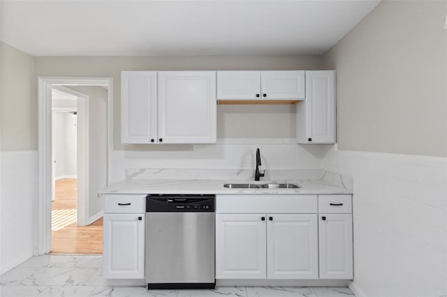 kitchen featuring white cabinets, light stone counters, stainless steel dishwasher, and sink